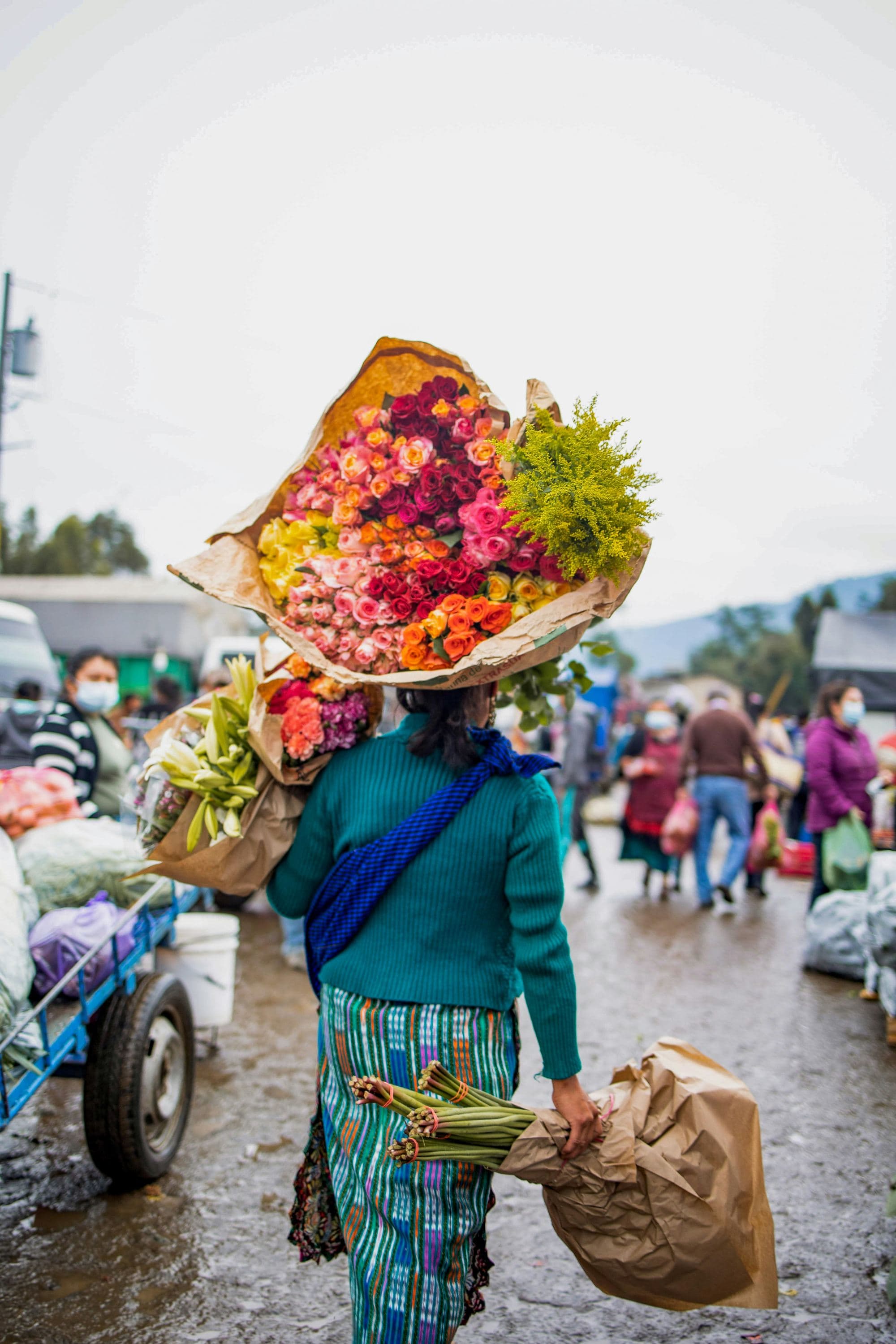 A flower vendor carries her goods through a market